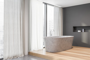 Corner of loft grey bathroom with stone tub