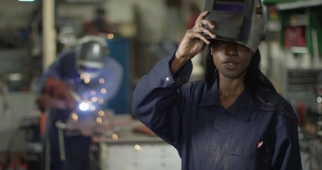 4K Portrait sexy & confident female welder working in garage workshop. Slow motion.