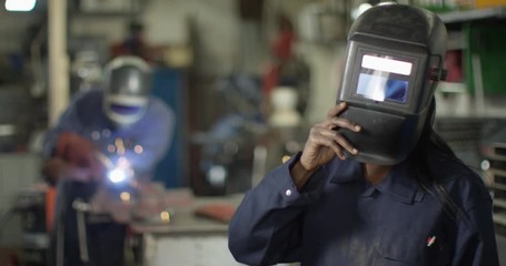 4K Portrait happy smiling female welder working in garage workshop. Slow motion.