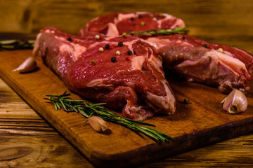 Raw ribeye steak, spices, rosemary and garlic on cutting board