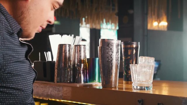 Young professional bartender effectively pours various drinks into a shaker