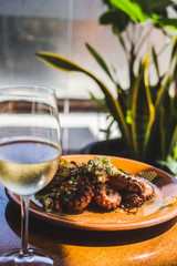 Plato con pulpos con verduras y copa de vino blanco