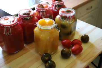 Tomatoes of different varieties with different juices in glass jars homemade preparations