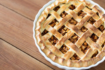 food, culinary and baking concept - close up of apple pie in mold on wooden table