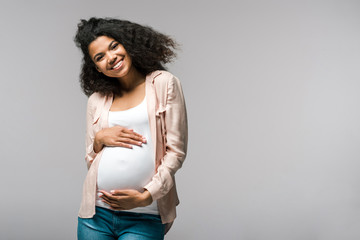 happy young pregnant african american woman touching belly on grey - Powered by Adobe