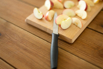 fruits, food cooking and eating concept - sliced apples and kitchen knife on wooden cutting board