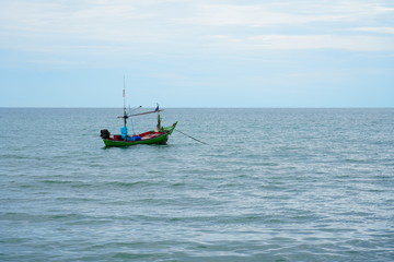Fototapeta na wymiar A fisher boat is floating on the sea alone before sunset.
