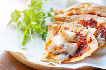 Set of crispy shrimp baked with chilli sauce and vegetable on paper and Thai parsley in wooden dish.