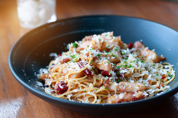 Spicy spaghetti with bacon serve in black plate.