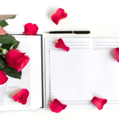 Red rose, red petals and a Bible on a white table. With journal, black pen and space for text. Clean white background. Baselland, Switzerland - 30.04.2019. 