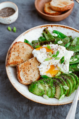 Healthy breakfast or lunch. Fried snow peas, avocado, poached eggs are sprinkled chia seeds with toasts.