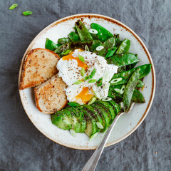 Top view of healthy breakfast or lunch. Fried snow peas, avocado, poached eggs are sprinkled chia seeds with toasts.