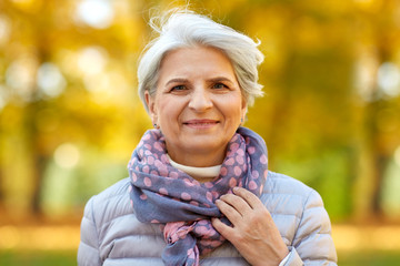 old age, retirement and season concept - portrait of happy senior woman at autumn park