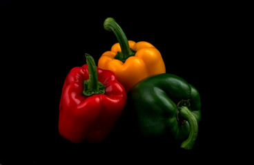 Three different colored of capsicums  isolated on black background