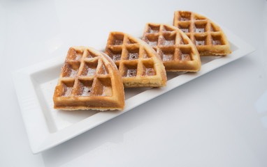 Triangle shape waffles are arranged in rows on a white plate