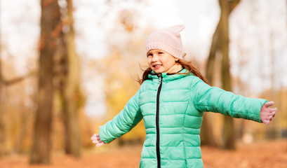 childhood, season and people concept - happy little girl at autumn park