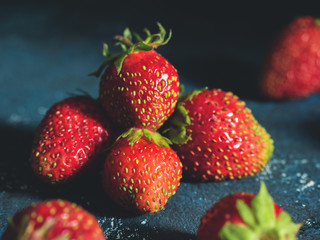 Ugly garden fresh ripe strawberry on a dark blue background. Real organic food