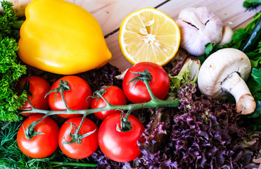 Vegetables and greens on wooden background. Pepper, dill, garlic, lemon, cherry tomatoes.