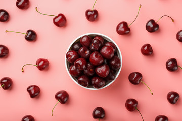 Cherry berry on a pink background in a white cup, top view.