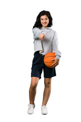 A full-length shot of a Young woman playing basketball points finger at you with a confident expression over isolated white background