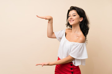 Young woman over isolated background holding copyspace to insert an ad