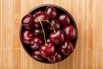 Ripe and juicy cherry berries on a wooden background in a brown cup