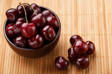 Ripe and juicy cherry berries on a wooden background in a brown cup