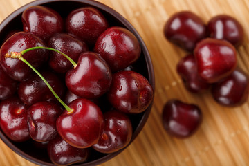 Ripe and juicy cherry berries on a wooden background in a brown cup