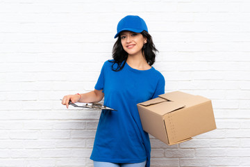 Young delivery woman over white brick wall
