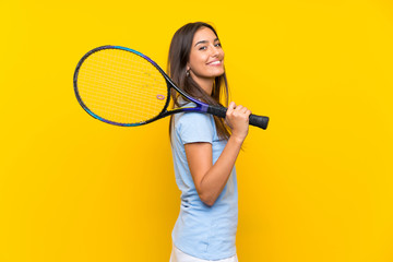 Young tennis player woman over isolated yellow wall