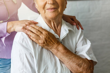 Elderly female hand holding hand of young caregiver at nursing home.Geriatric doctor or geriatrician concept. Doctor physician hand on happy elderly senior patient to comfort in hospital examination - obrazy, fototapety, plakaty