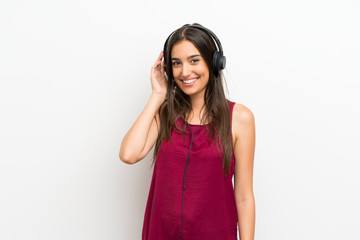 Fototapeta premium Young woman over isolated white background listening to music with headphones
