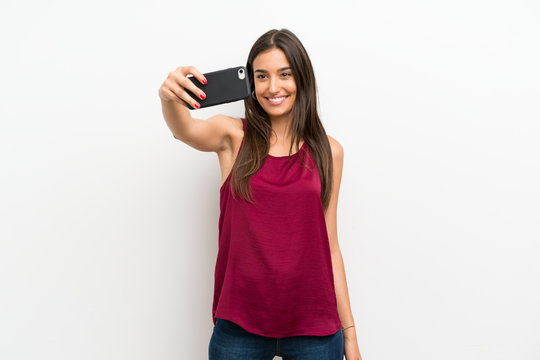 Young woman over isolated white background making selfie with cellphone