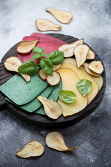 Different types of sliced cheese with pear chips and green basil, selective focus, vertical shot