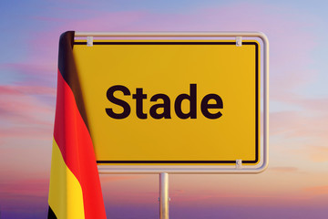 Stade. Gelbes Schild/Ortsschild. Flagge von Deutschland hängt darüber. Himmel mit Sonnenuntergang oder Sonnenaufgang