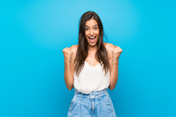 Young woman over isolated blue background celebrating a victory in winner position