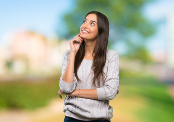 Young hispanic brunette woman thinking an idea while looking up at outdoors