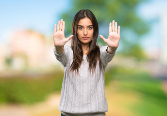 Young hispanic brunette woman making stop gesture and disappointed at outdoors