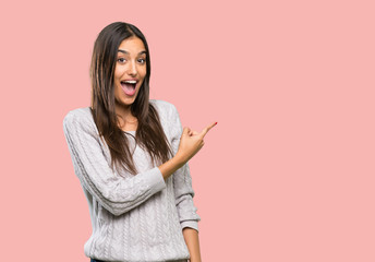 Young hispanic brunette woman surprised and pointing side over isolated background