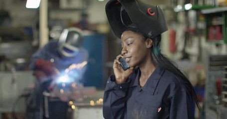 4K Smiling female mechanic talking on phone in garage workshop