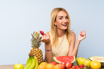 Happy  Young blonde woman with lots of fruits