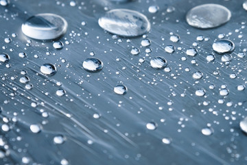 Close-up of raindrops of different sizes on the surface covered with cling film. Moisture weather and humidity concept