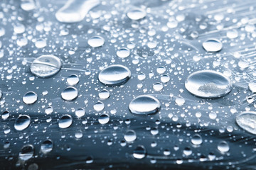 Close-up of raindrops of different sizes on the surface covered with cling film. Moisture weather and humidity concept