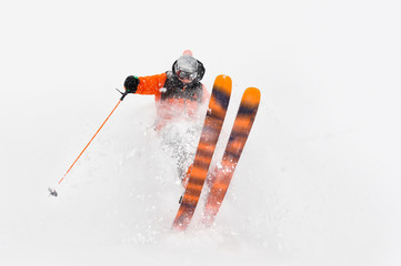 Professional Skier athlete rides out of deep snow while performing a skiing trick in a snowstorm....