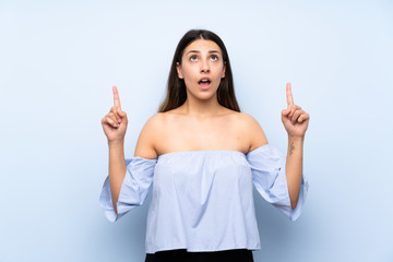 Young brunette woman over isolated blue background pointing with the index finger a great idea