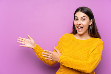 Young woman over isolated purple background extending hands to the side for inviting to come