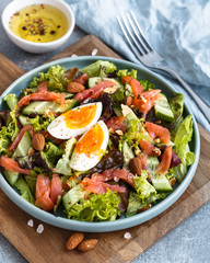Close-up of blue plate with salmon salad with cucumbers, eggs and cedar nuts