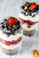 Two pieces of puff glass dessert with granola, mascarpone cream, strawberry, blueberry and walnuts