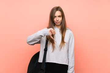 Young sport woman over isolated pink background showing thumb down sign