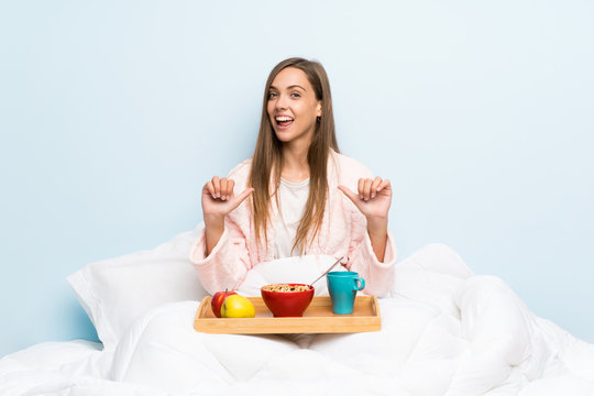 Young woman in dressing gown with breakfast proud and self-satisfied